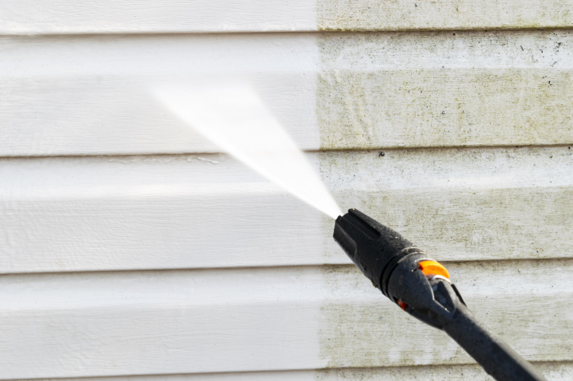 A man pressure washing a house.