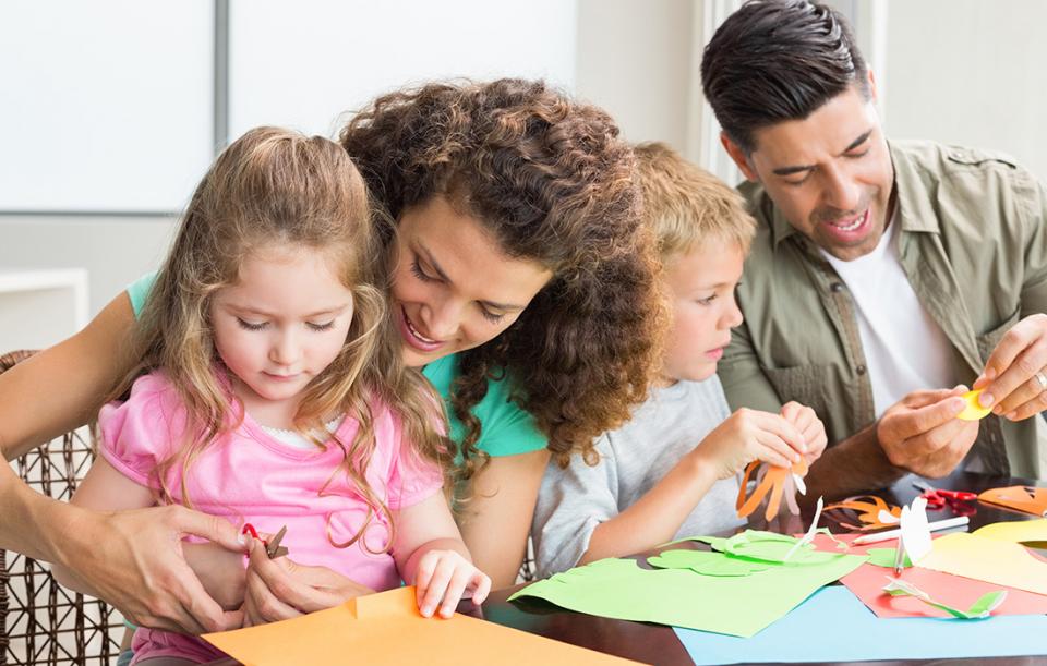 A family is making crafts at home with their children and learning together.