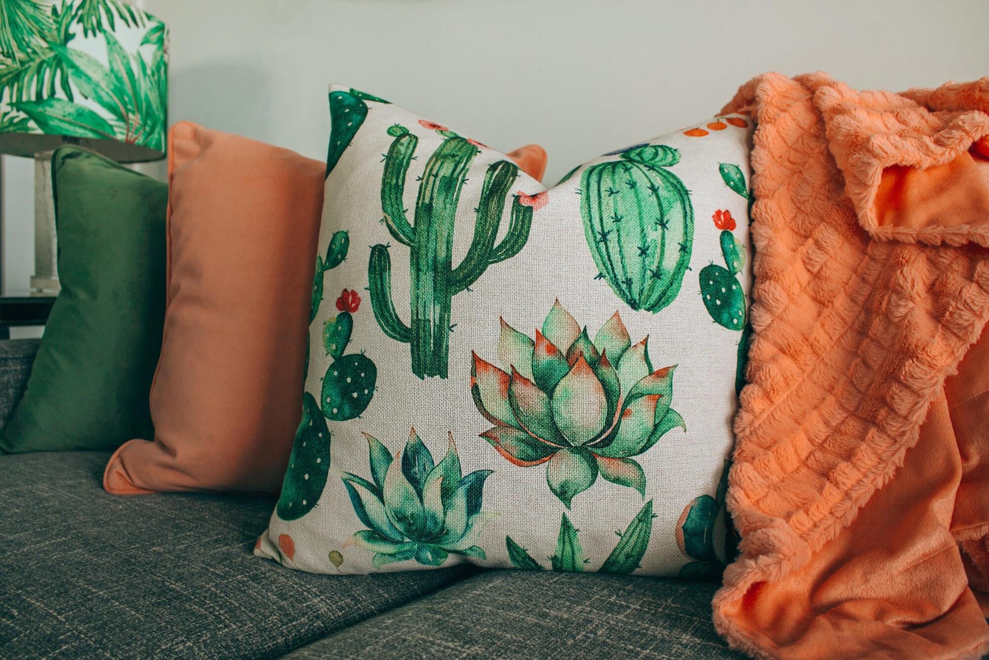 Cactus pillows on a couch with an orange throw, featuring bamboo pillow benefits.