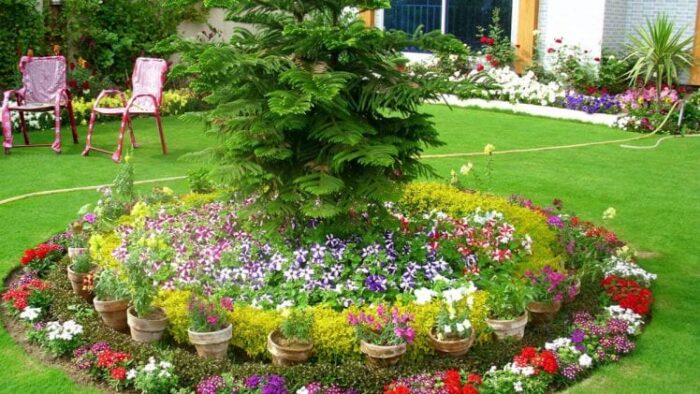 A beautifully landscaped garden with colorful flowers and a tree in the middle.