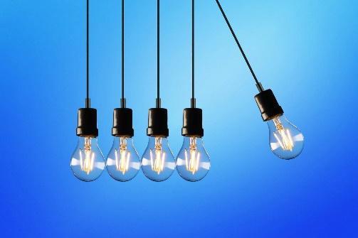 A group of energy-efficient light bulbs hanging on a blue background.