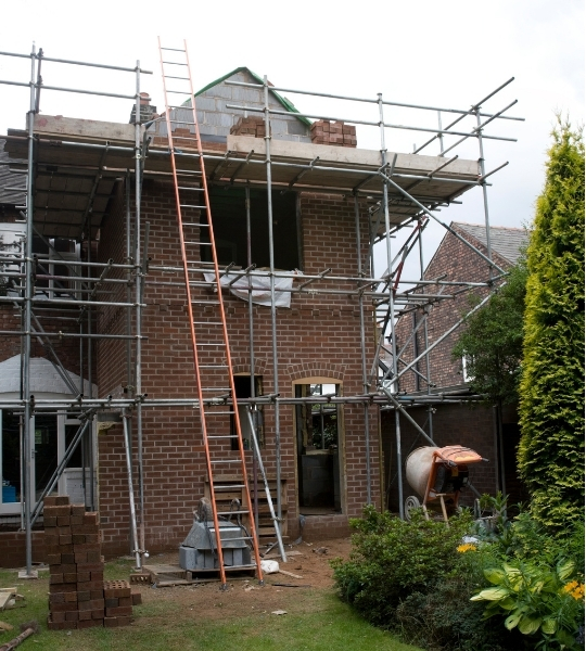 A house being built with scaffolding and an extension ladder.