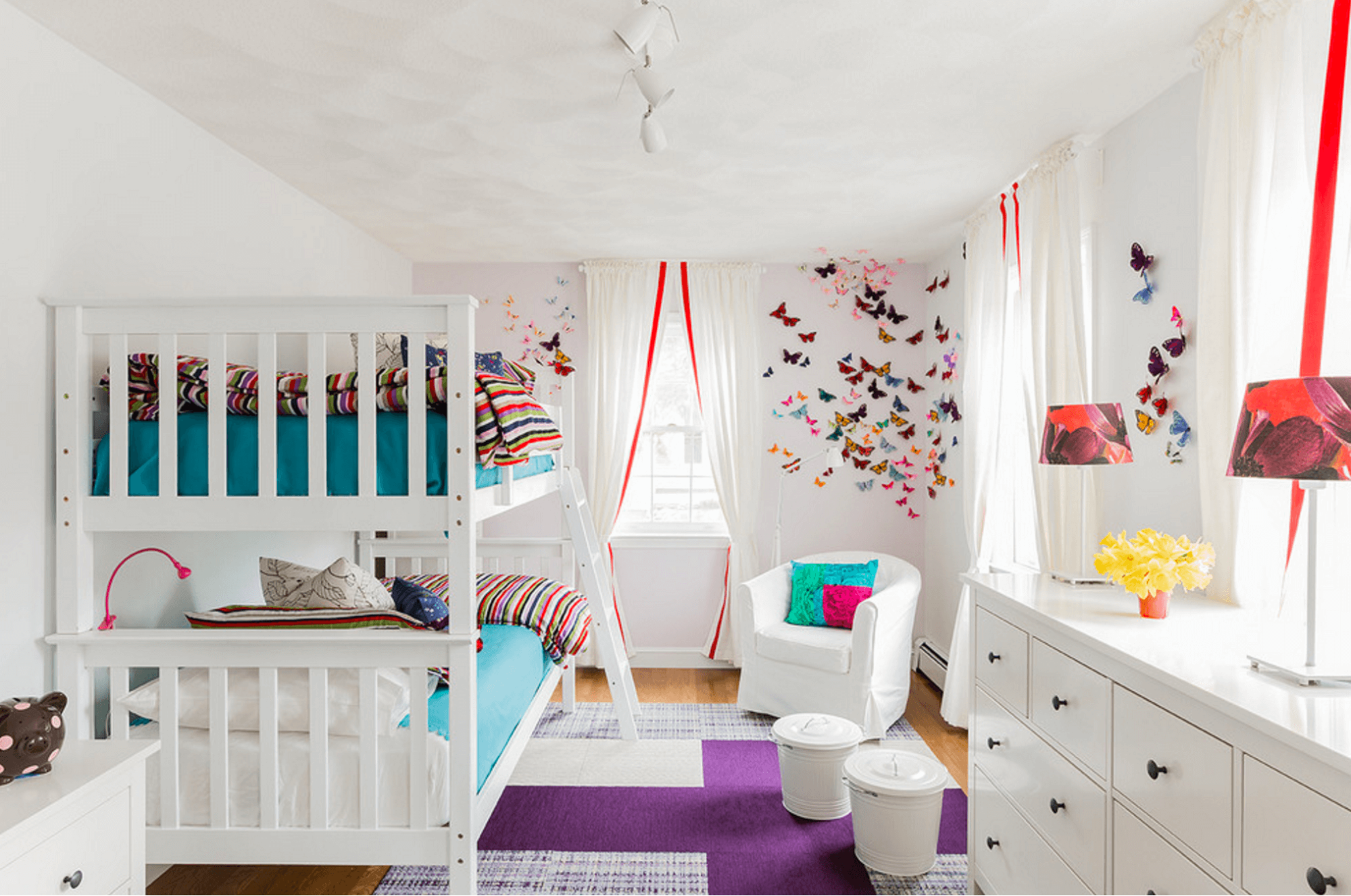 A colorful kids' room with a white bunk bed and a colorful rug.