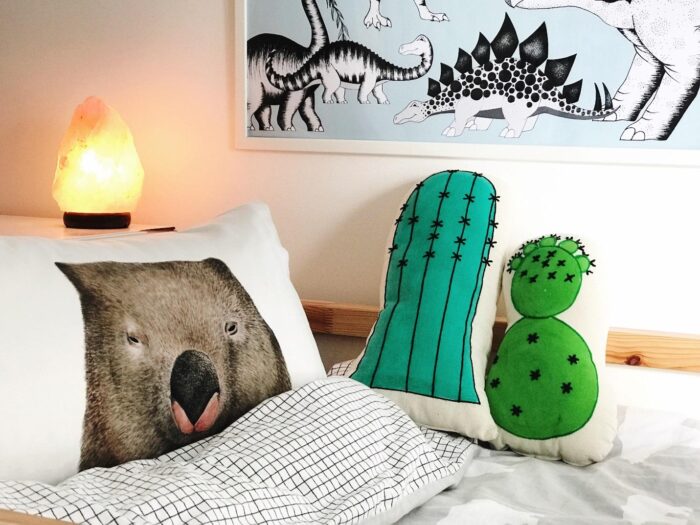 A kid's room with dinosaur pillows.