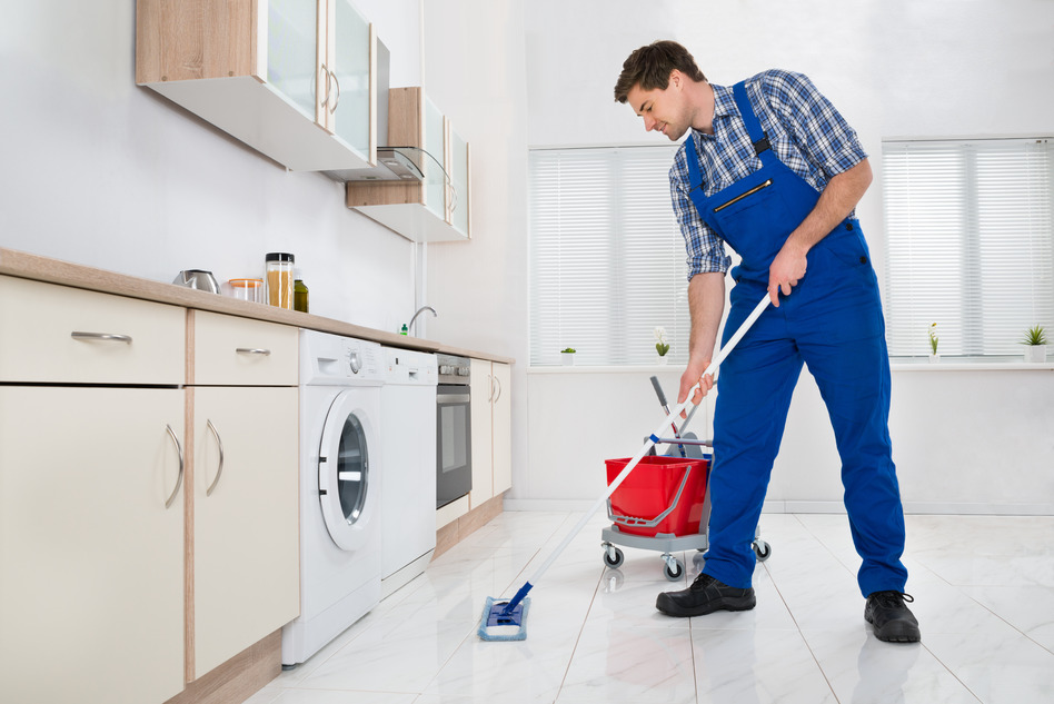 A man providing cleaning services in a kitchen with a mop.