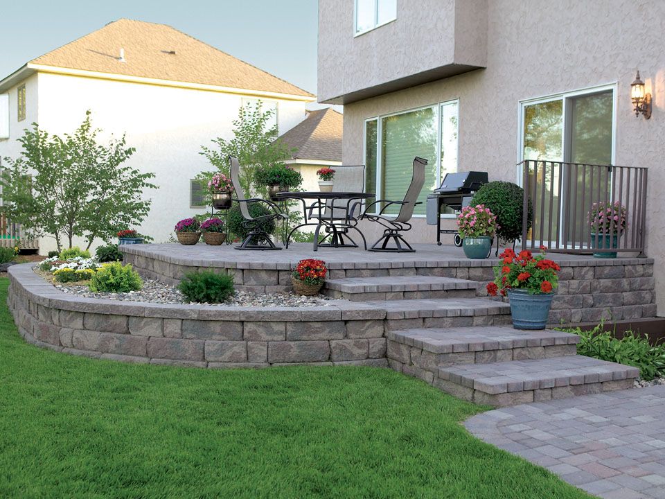 A backyard with a patio, steps, and a retaining wall.
