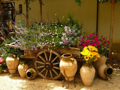 A budget-friendly wooden cart filled with pots of flowers for garden decoration.