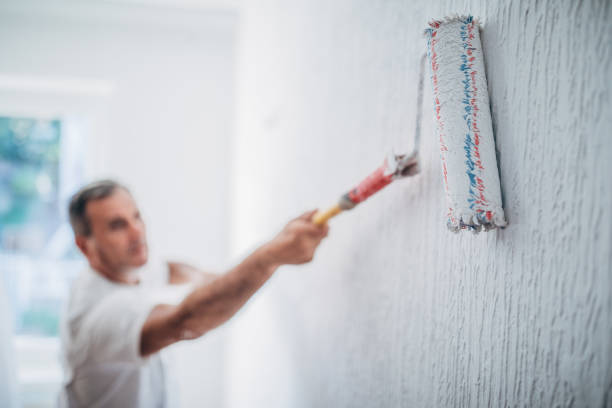 A man using a paint brush to paint a wall.