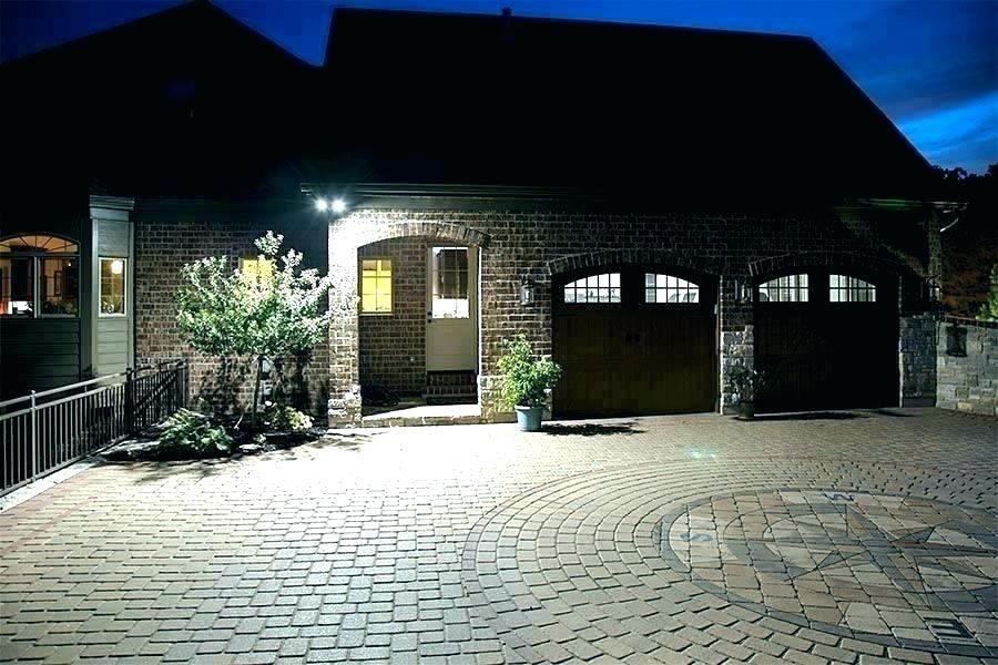 A house with a brick driveway illuminated by LED lights at night.