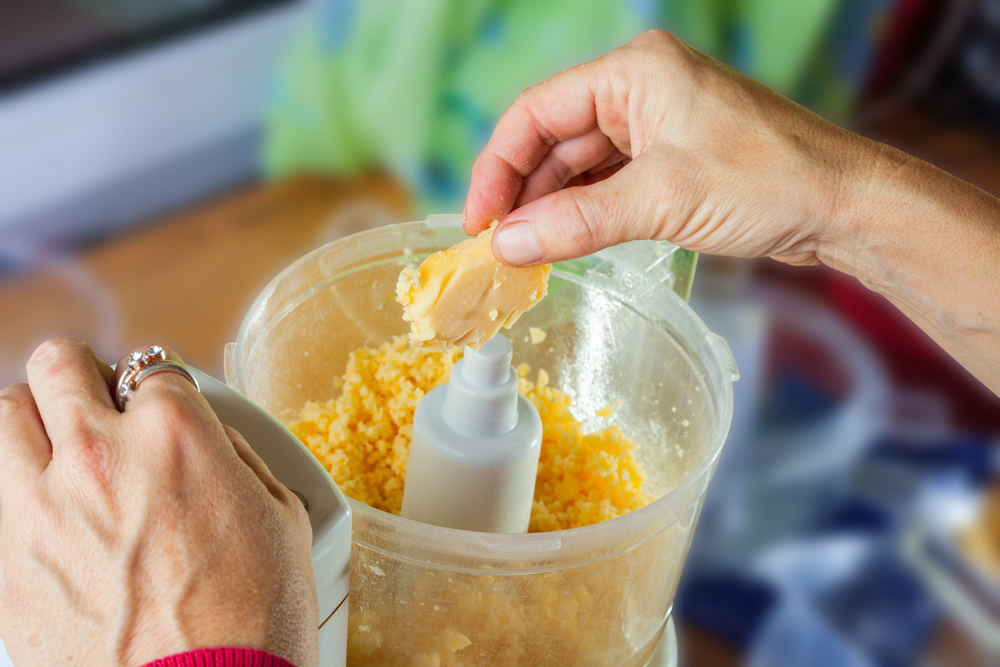 A person is using a food processor to process cheese.