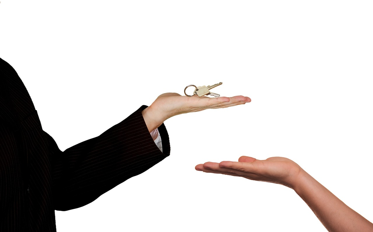 A woman handing a key to another person in order to buy a house.