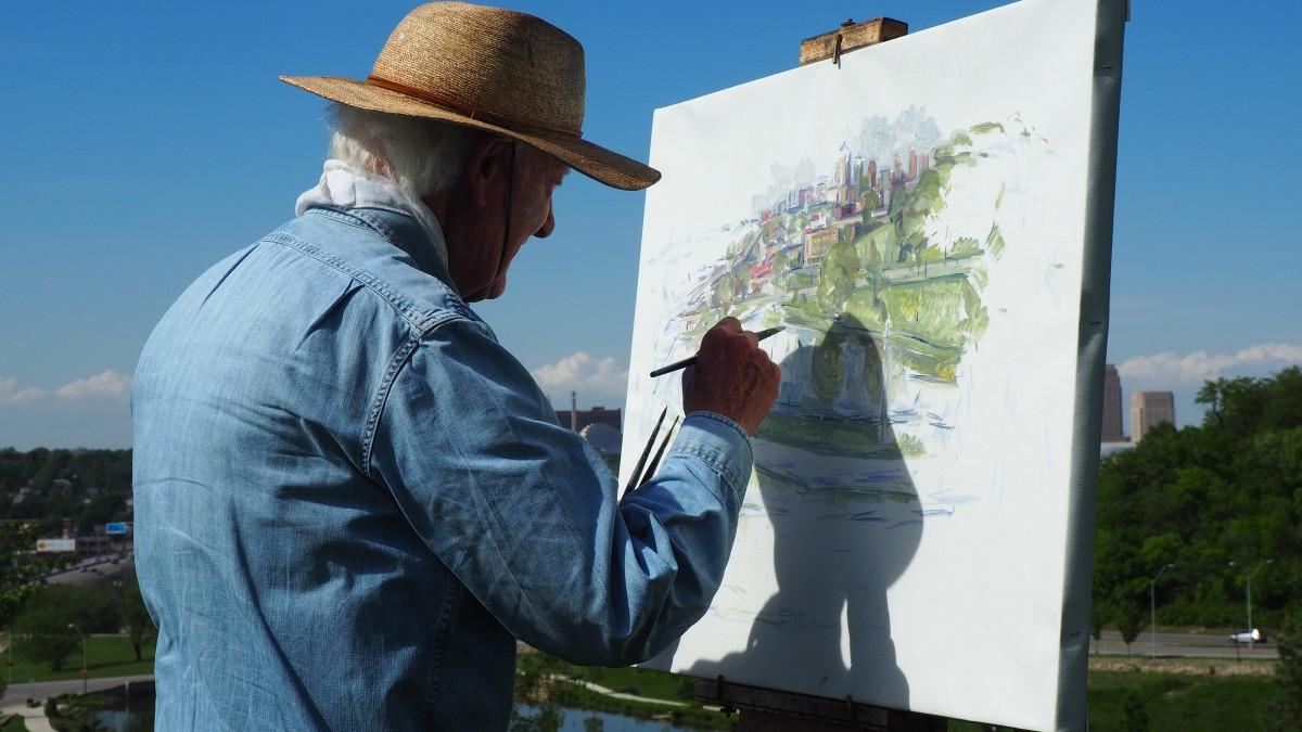 A man in a straw hat is transforming photos into paintings.