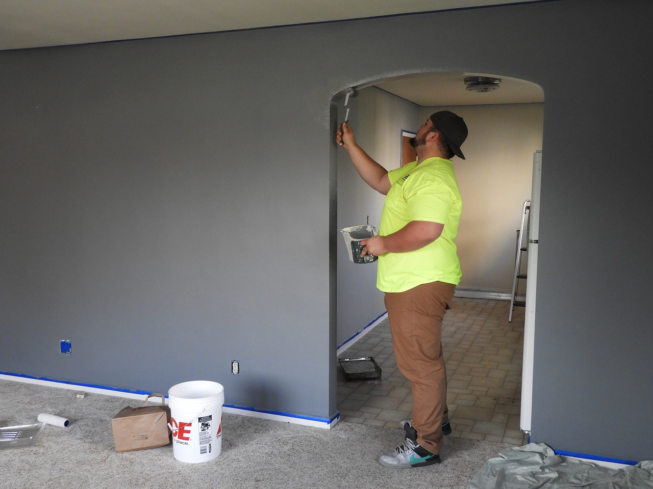 A man improving his home by painting a room with gray walls.
