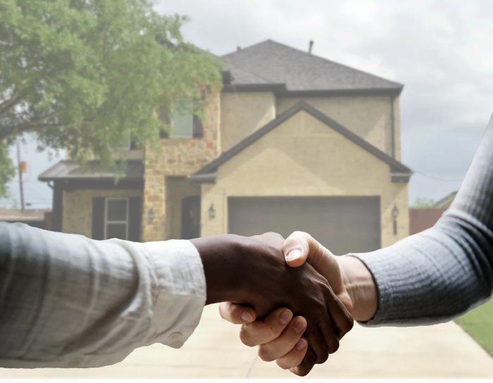 Two people shaking hands to buy a house.
