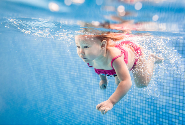 A little girl swimming underwater in a swimming pool. (Keywords: girl, swimming)