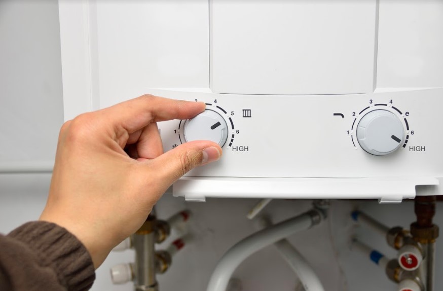 A person adjusting a water heater knob.