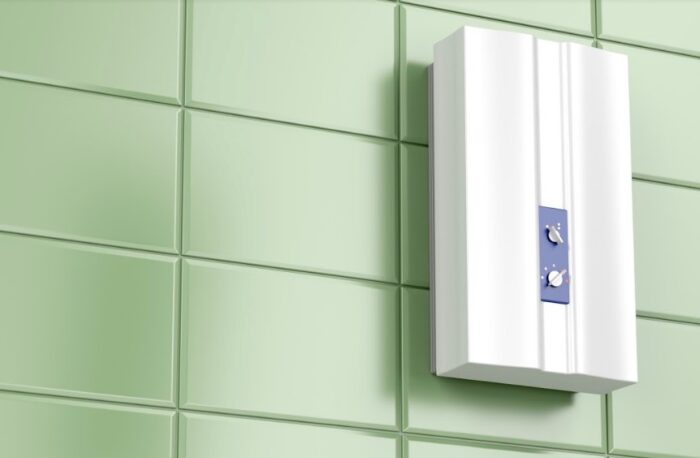 A white wall mounted water heater on a green tiled wall.