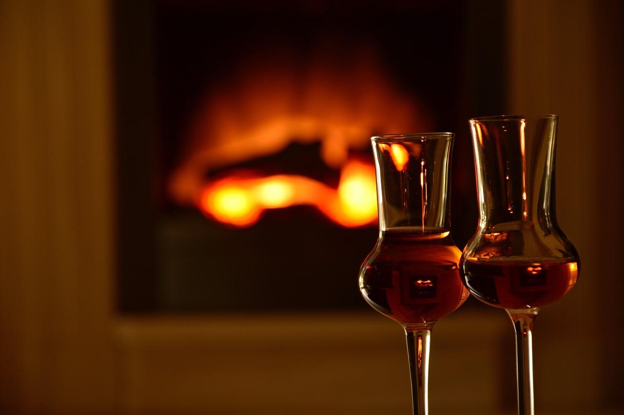 Two glasses of wine in front of a fireplace.