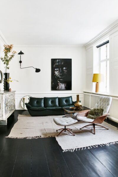 A living room with black hardwood floors and a black sofa.