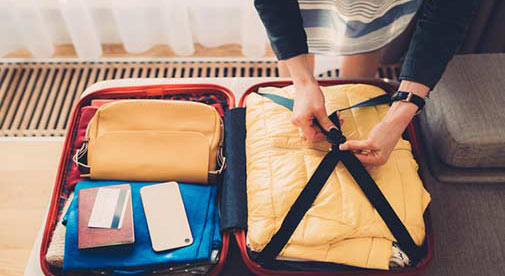 A woman is packing clothes into a suitcase to move out of the USA.