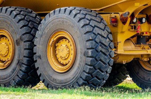The tires of a construction project's dump truck are parked in a grassy area.