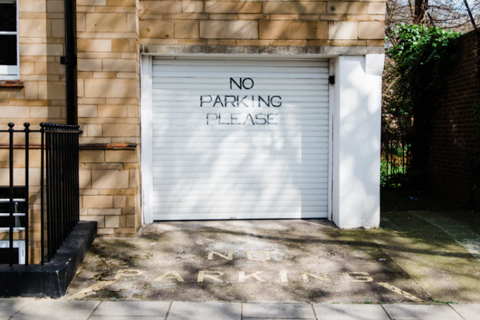 A paved driveway with a sign that says no parking please.