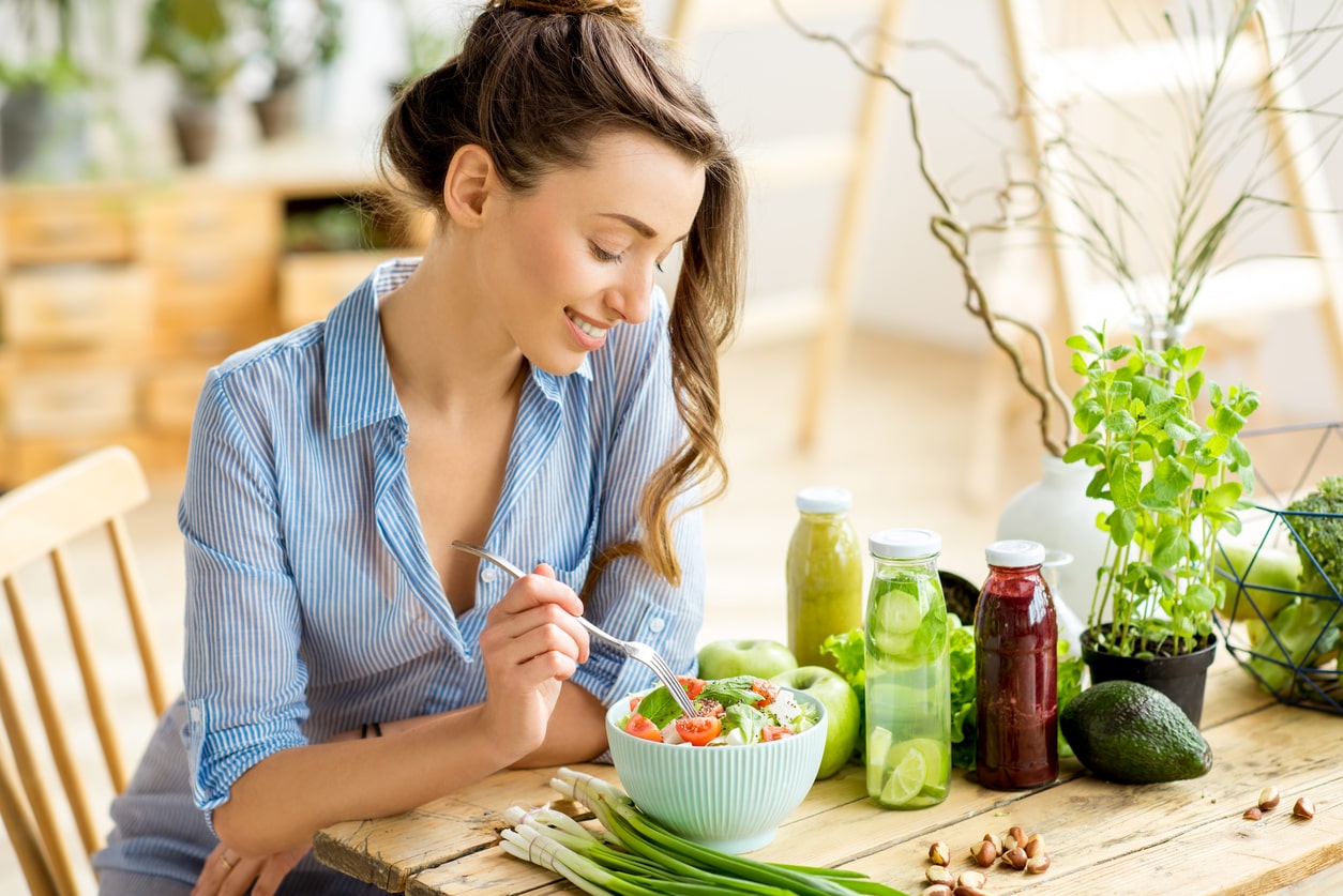 A woman enjoying a simple meal at a table with a bowl of vegetables.