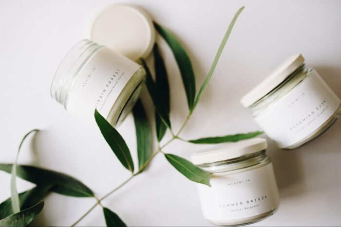 Three eco-friendly jars with eucalyptus leaves on a white surface.