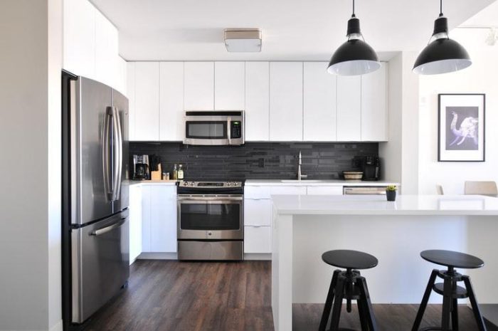 A kitchen with black and white cabinets and stools that require regular cleaning.