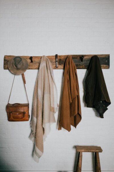 An eco-friendly coat rack with coats and hats hanging on it, perfect for redecorating your space.