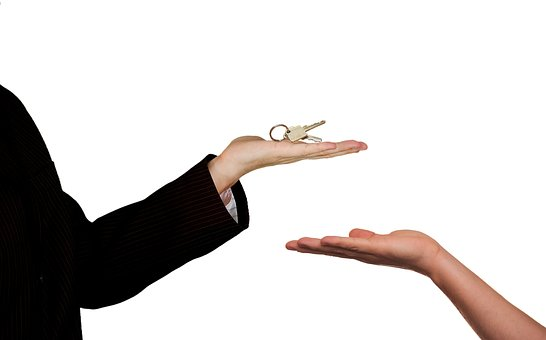 A woman handing a key to another person during a home buying process.