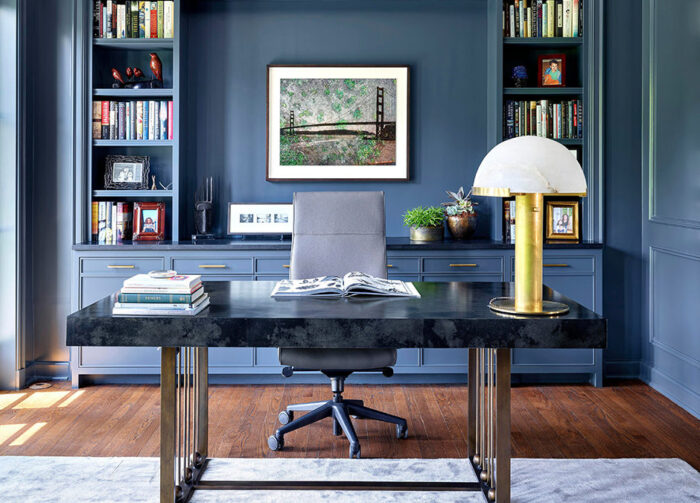 A blue home office with a desk and bookshelves featuring office decor.