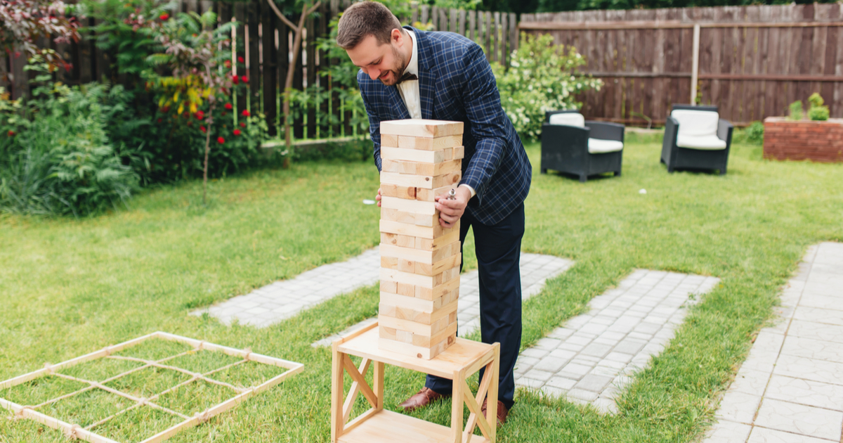 A man in a suit is playing a game of jenga at a wedding.