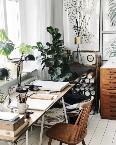 A plant-filled home office with a desk.