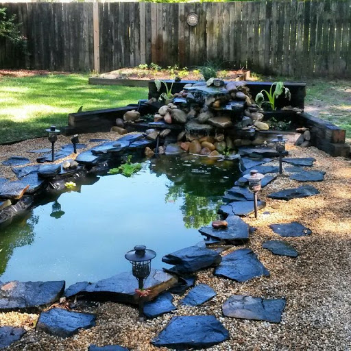 A garden pond with rocks and a waterfall.