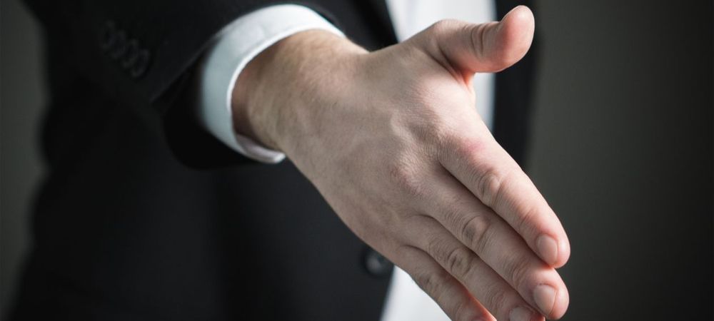 A man in a suit is offering a handshake with Bully Offers.
