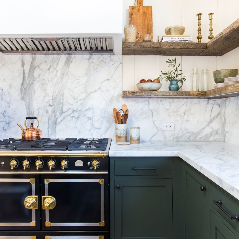 A kitchen with green cabinets and marble countertop.