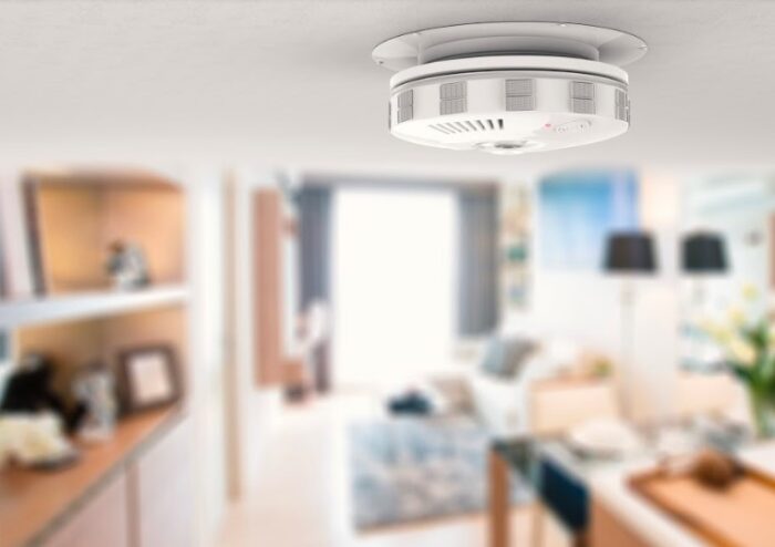 A smoke detector ensuring home safety hanging from the ceiling in a living room.