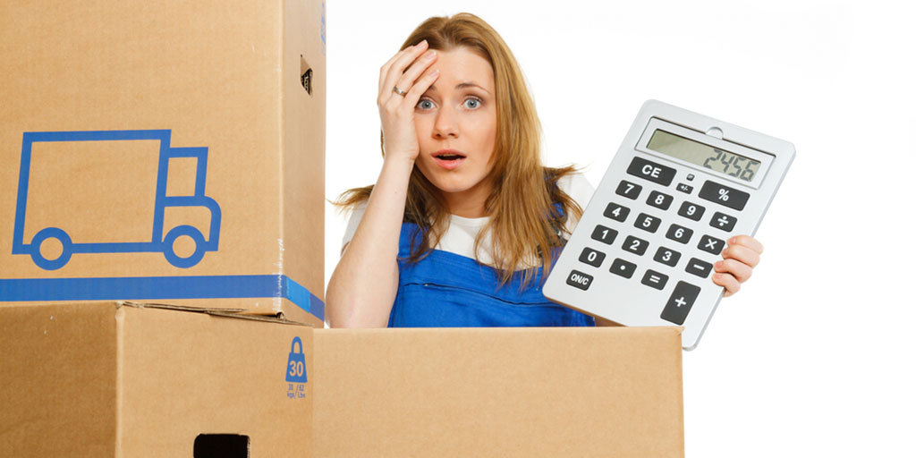 A woman holding a calculator in front of moving boxes.