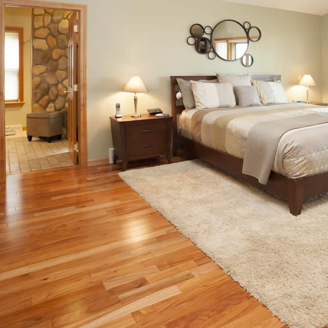 A bedroom with hardwood floors and a bed. (Types of Flooring)