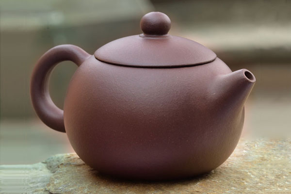 A teapot sits on top of a rock.