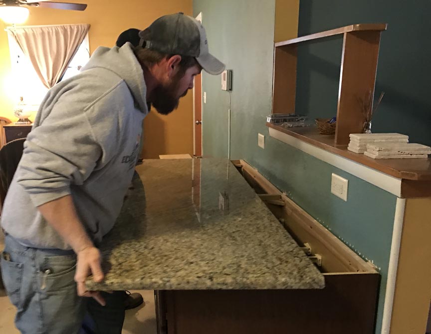 A man measuring and installing granite countertops in a kitchen.