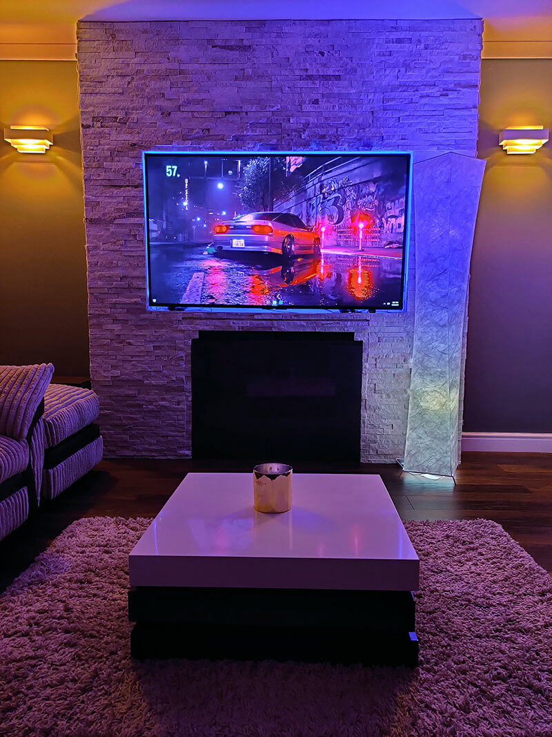 The mood lighting in the home is enhanced by the tv on the wall.