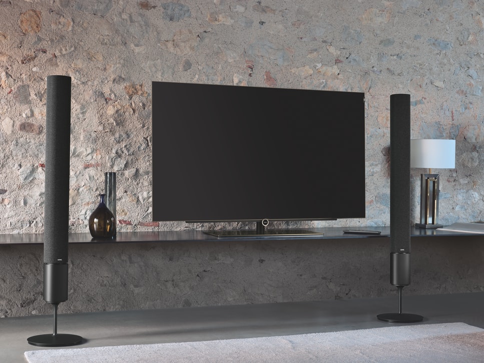 A black TV stands on top of a stone wall, demonstrating how to incorporate speakers.