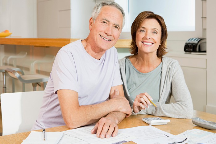 An older couple involved in retirement planning, sitting at a table with paperwork.
