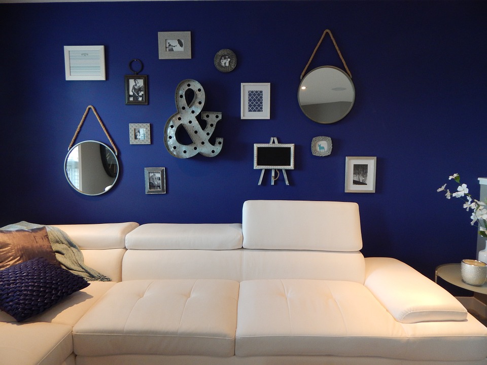 A living room with subtle improvements, such as a white couch and mirrors on the wall.