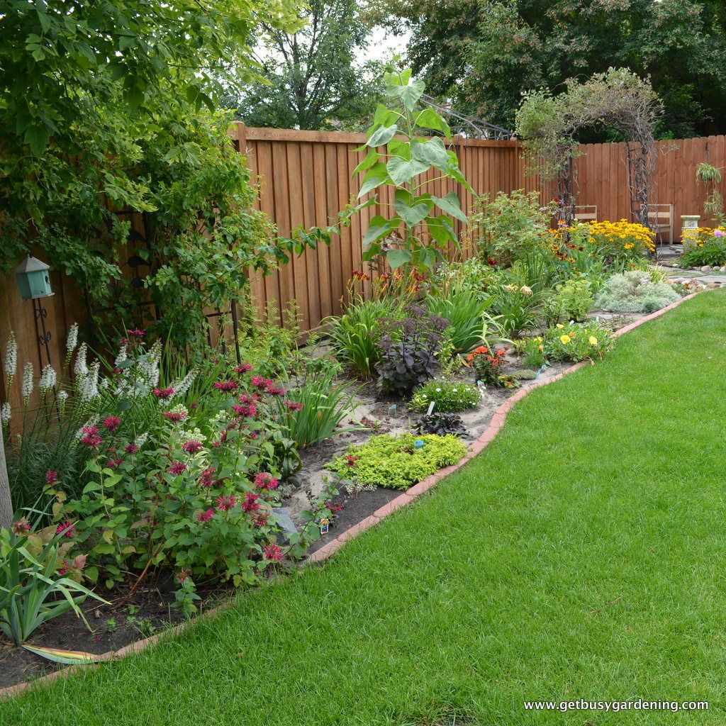 A garden with a wooden fence and flowers.