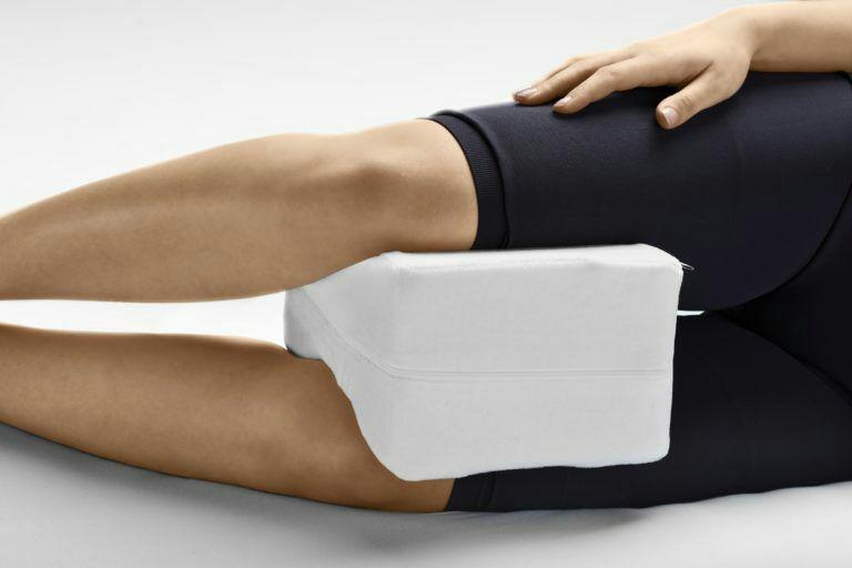A woman using a knee pillow while reclining.