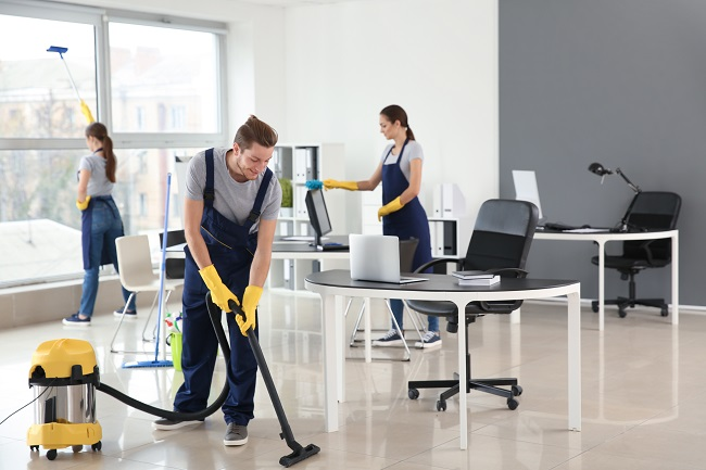 A group of office cleaners using a vacuum cleaner.