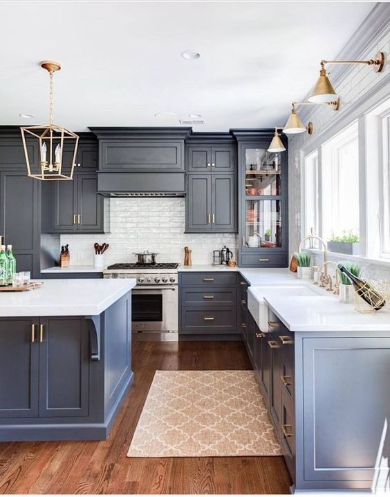 A kitchen with blue cabinets enhanced by gold accents and well-lit in three important areas.